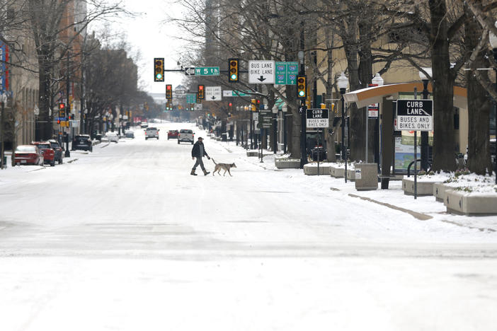 A man walks his dog downtown after a snowstorm this week in Fort Worth, Texas. The winter storm has brought historic cold weather and power outages to more than two dozen states, with a mix of freezing temperatures and precipitation.