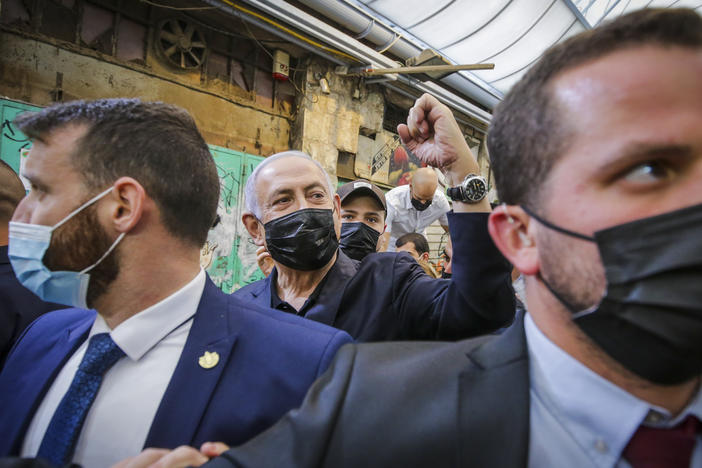 Israeli Prime Minister Benjamin Netanyahu, center, waves to supporters as he tours the Mahane Yehuda market while campaigning a day before national elections, in Jerusalem on Monday.
