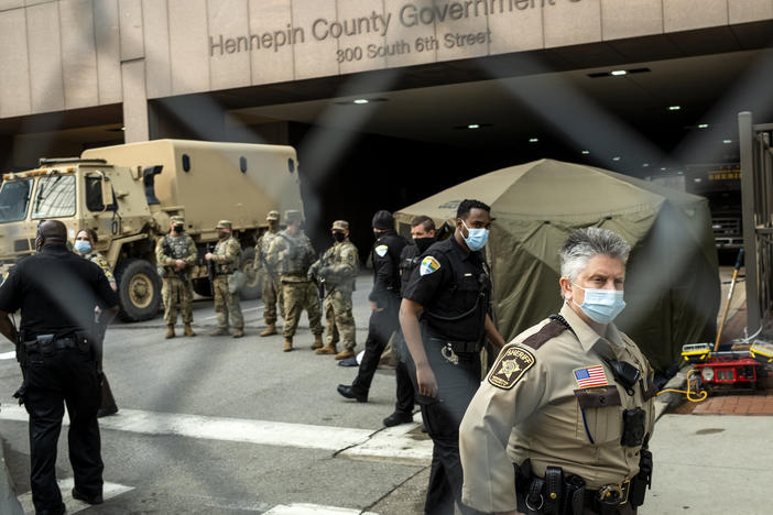Jurors are escorted into the Hennepin County Government Center by sheriff's deputies. Here, members of the Minnesota National Guard and other agencies stand watch outside the building in Minneapolis.
