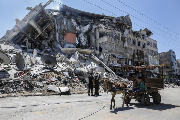 Palestinians walk past the debris of the Al-Sharouk tower in Gaza City, which collapsed after being hit by an Israeli air strike.