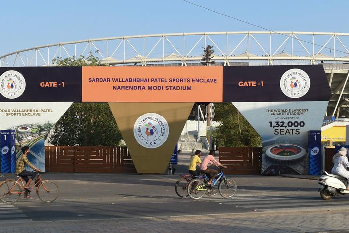 Cyclists cycle past the main entrance of the Narendra Modi Stadium in Ahmedabad, India, a venue where cricket matches were taking place during the 2021 Indian Premier League — until it was suspended.