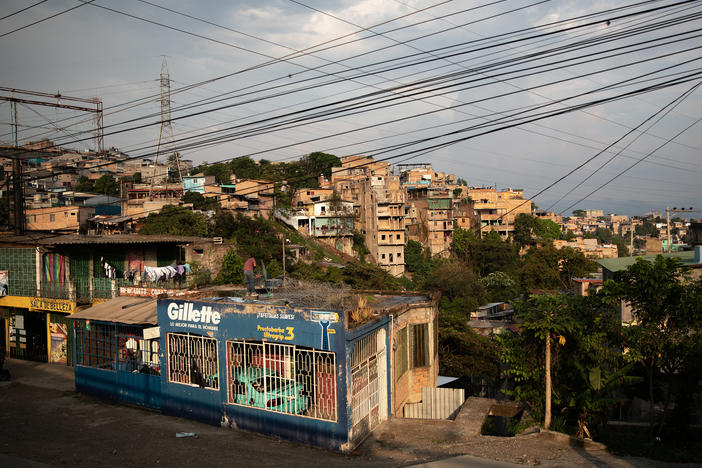 A man cleans a rooftop as the sun sets over the embattled Pedregal neighborhood of Tegucigalpa.