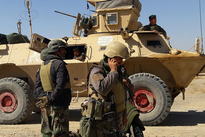 Afghan security forces stand near an armored vehicle during ongoing fighting with the Taliban in the Busharan area on the outskirts of Lashkar Gah, the capital city of Helmand province, on May 5.