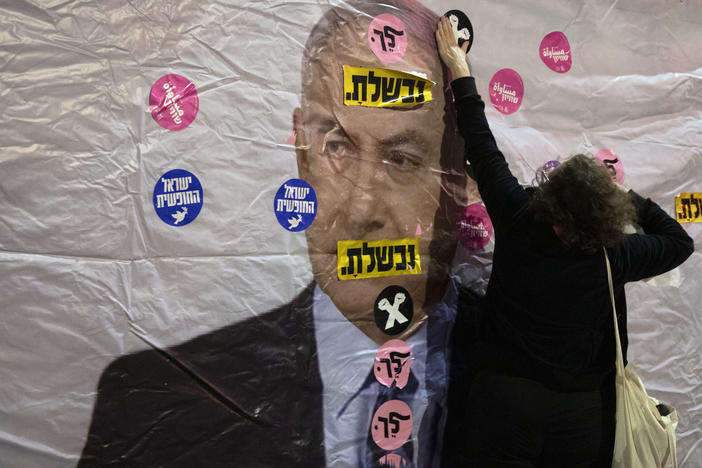 An Israeli protester places a sticker on a banner showing Israeli Prime Minister Benjamin Netanyahu during a demonstration outside the prime minister's residence in Jerusalem on June 5. The Hebrew reads: "You failed" and "Leave."