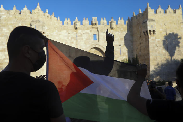 Demonstrators wave the Palestinian flag during a protest in Damascus Gate, just outside Jerusalem's Old City on June 19. Palestinians and Jewish settlers hurled stones, chairs and fireworks at each other in a tense Jerusalem neighborhood, where settler groups are trying to evict several Palestinian families, officials said Tuesday.
