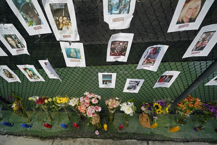 A memorial near the Champlain Towers disaster site holds photos of missing persons in Surfside, Fla. Rescuers continue their search for survivors, but have confirmed that nine people are dead and more than 150 are still missing.