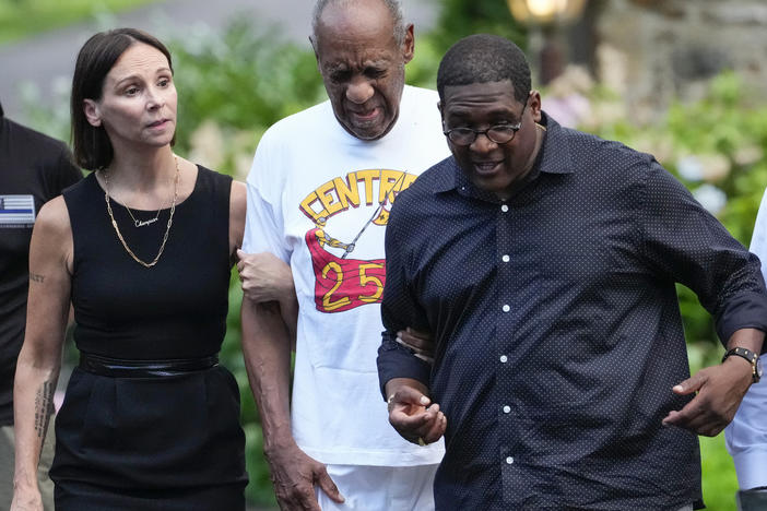Bill Cosby (center) approaches members of the media gathered outside his home in Cheltenham, Pa., with his spokesperson Andrew Wyatt. On Wednesday, Pennsylvania's highest court overturned Cosby's sex assault conviction, and he was released from prison.