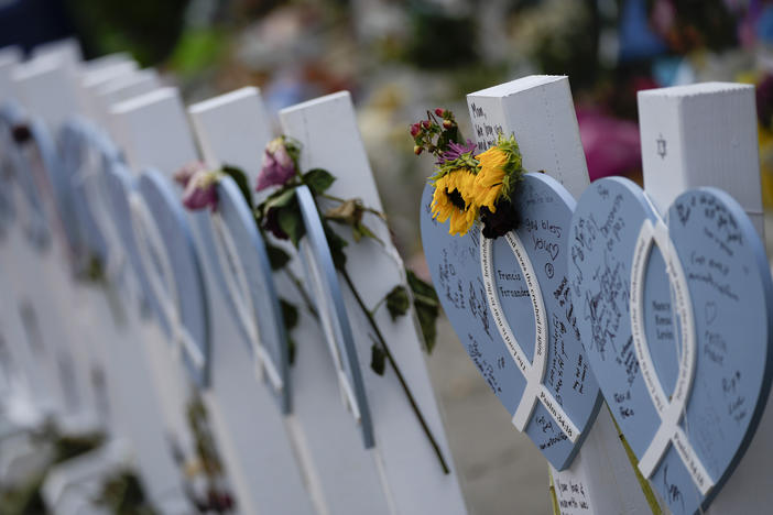Flowers and messages of love adorn wooden hearts with the names of victims of the Champlain Towers South building collapse, at a makeshift memorial near the site, on Monday, July 12.