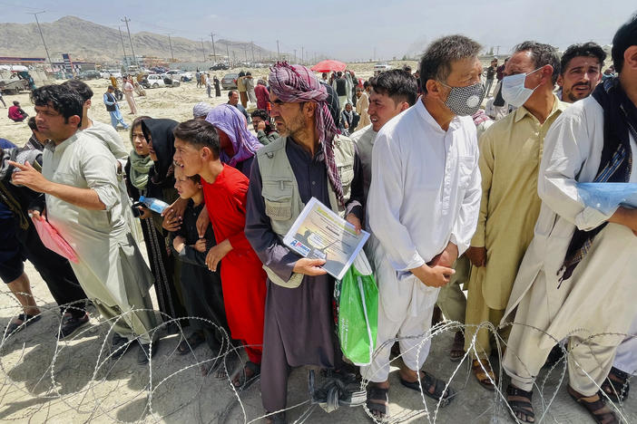 A man holds a certificate acknowledging his work for Americans as hundreds of people gather outside the international airport in Kabul, Afghanistan, Tuesday.