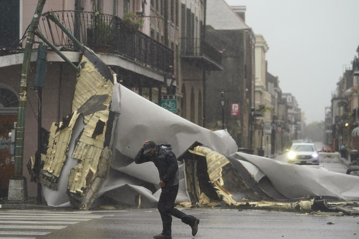 A man passes by a section of roof that was blown off of a building in the French Quarter by Hurricane Ida winds on Sunday in New Orleans.