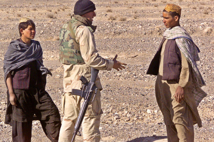 Cpl. Ajmal Achekzai, 26, who served as a translator for the 15th Marine Expeditionary Unit, talks with two Afghan locals in December 2001 at the perimeter of a patrol base in southern Afghanistan.