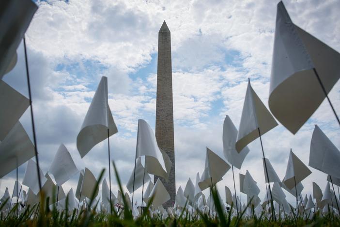 White flags stand near the Washington Monument on Tuesday during installation of a temporary art exhibit on the National Mall. More than 630,000 flags are part of artist Suzanne Brennan Firstenberg's <em>In America: Remember</em>, honoring Americans who have died of COVID-19.