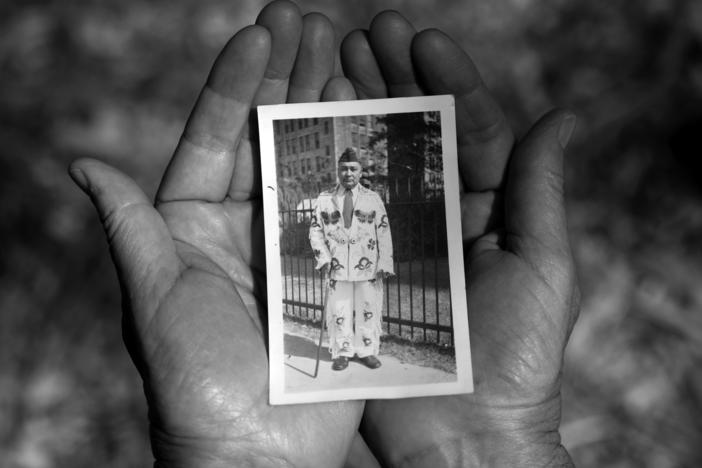 Sheridan MacKnight holds a photograph of her grandfather John B. McGillis. In the photograph, McGillis wears a hand-made beaded buckskin suit and a U.S. army cap from his service in WWI.