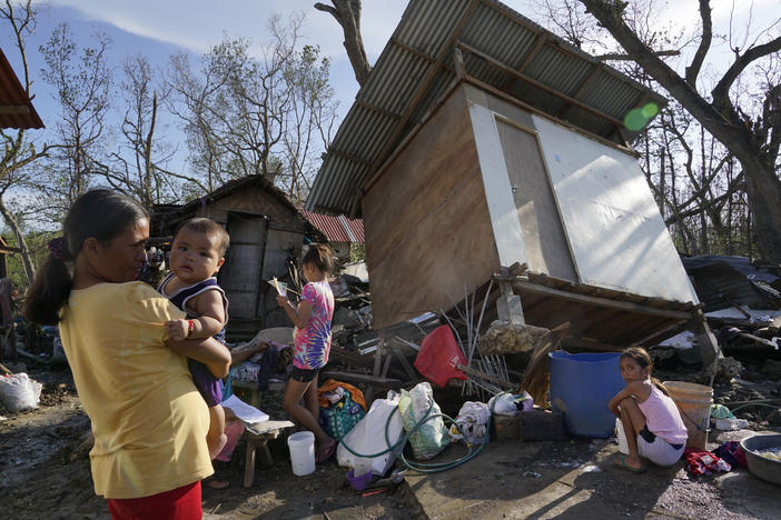 Residents stand amid damaged homes following Typhoon Rai in Talisay, Cebu province, central Philippines on Saturday, Dec. 18, 2021. The strong typhoon engulfed villages in floods that trapped residents on roofs, toppled trees and knocked out power in southern and central island provinces, where more than 300,000 villagers had fled to safety before the onslaught, officials said.