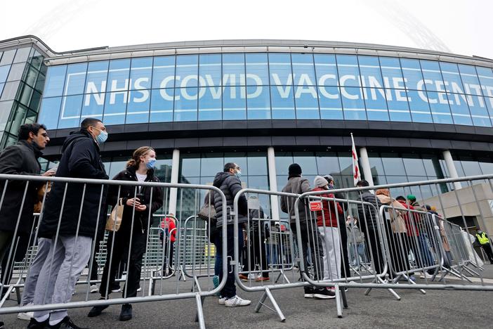People queue outside the newly set up vaccination center at London's Wembley Stadium to receive a COVID-19 vaccine or booster on Sunday, as the booster rollout accelerates in England and case numbers spike.