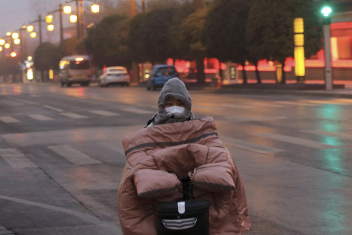 A woman wearing a face mask to protect against COVID-19 rides down a mostly empty street in Xi'an in northwestern China's Shaanxi Province, Thursday, Jan. 6, 2022.