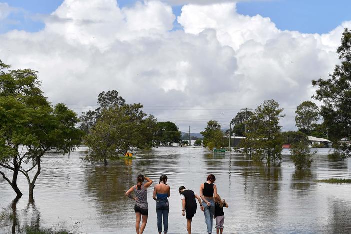A family stays next to a flooded street in Lawrence, Australia, some 45 miles from the New South Wales town of Lismore, on Tuesday.