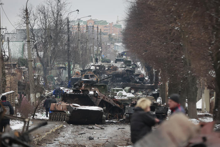 People look at the gutted remains of Russian military vehicles on a road in the town of Bucha, close to the capital Kyiv, on Tuesday.