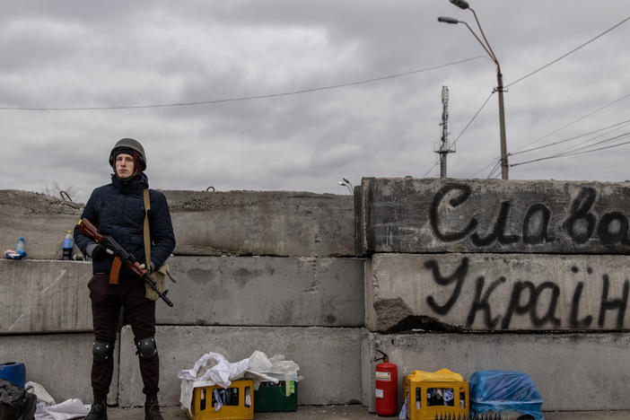 A member of a Territorial Defense unit guards a barricade next to writing saying "Glory To Ukraine" close to the eastern frontline on Saturday in Kyiv. Russia is continuing an assault on Ukraine's major cities.