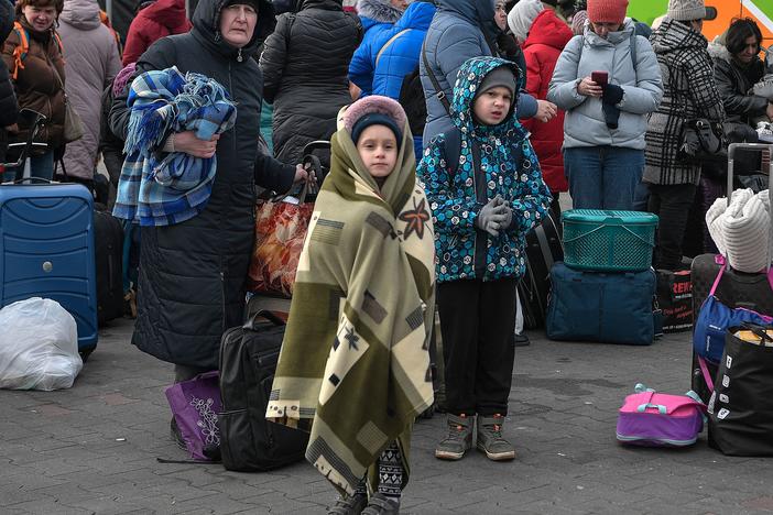 People wait to board buses taking them further into Poland or abroad from a temporary refugee shelter in a former shopping center near the Polish city of Przemysl on Tuesday.