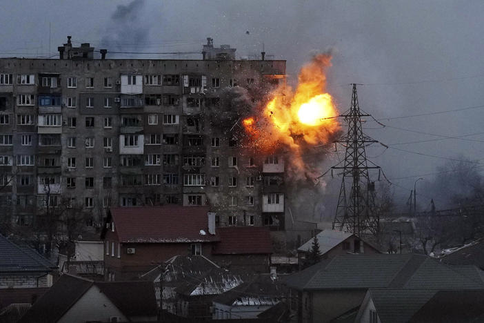 An explosion is seen in an apartment building after a Russian army tank fired in Mariupol, Ukraine, on Friday.