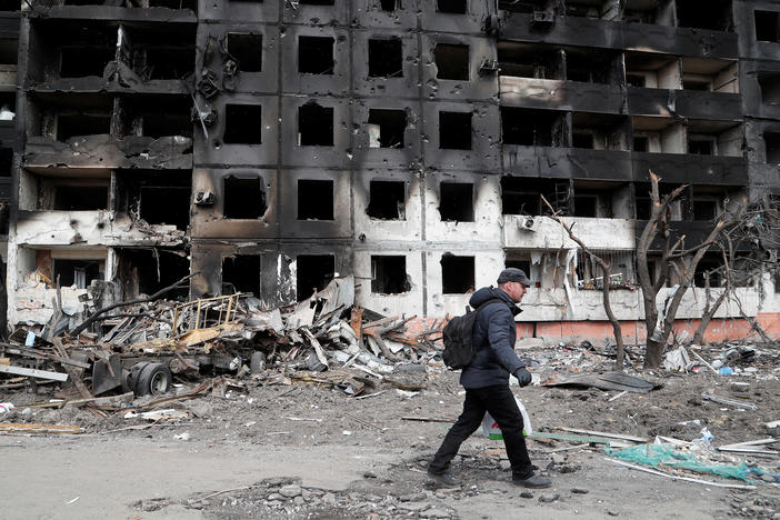 A man walks on Thursday near a block of flats destroyed in the besieged Ukrainian city of Mariupol.