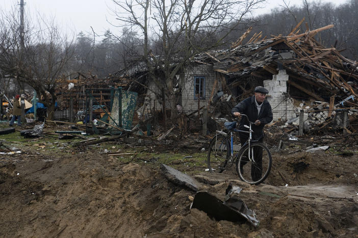 A resident walks his bicycle on a narrow path between craters made by artillery in a neighborhood of Chernihiv.