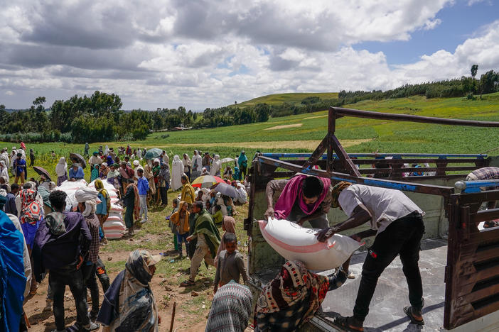 Volunteers unload food aid in Chena, Ethiopia, one of many parts of the world where conflict has fueled hunger.