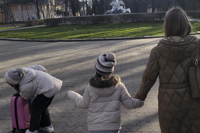 Kateryna Kltsova, right, with her two daughters Nadia, 7, center, and Maria, 11, left, with their new pink suitcase in a park in Lviv.