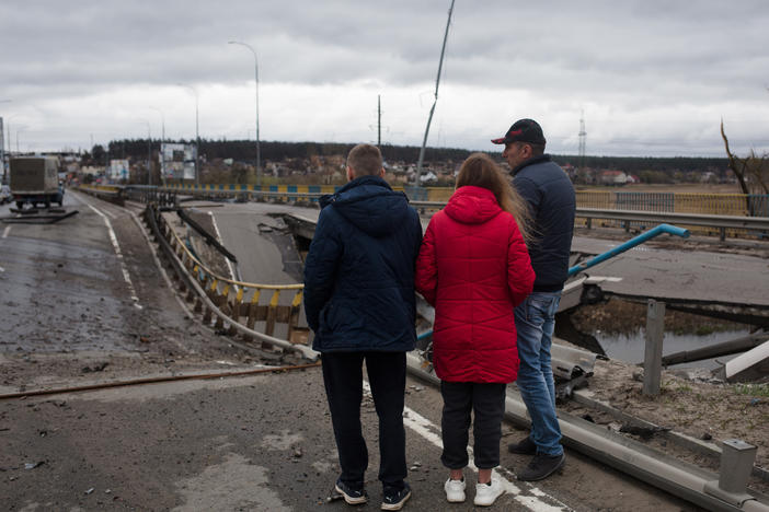 Residents of Irpin, Ukraine, near Kyiv stand on a damaged bridge on Saturday. Kyiv's mayor is urging people to remain vigilant after more strikes occurred overnight in the area.