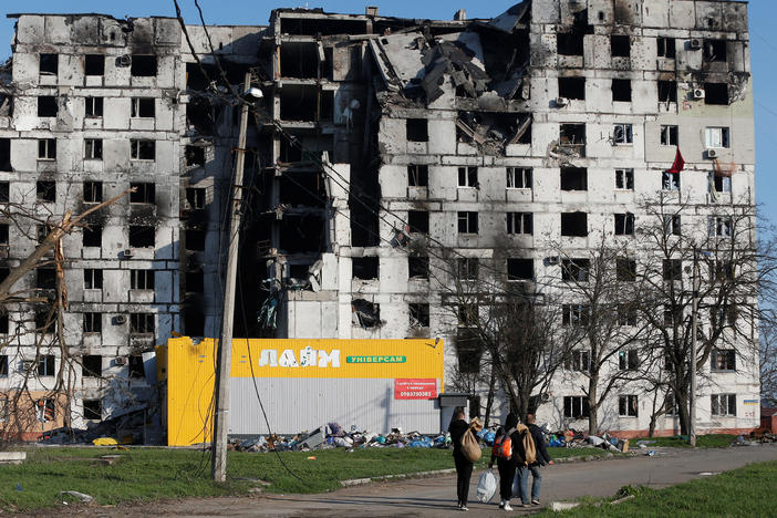 Residents walk past an apartment building on Wednesday in Mariupol, Ukraine, destroyed during the war with Russia.