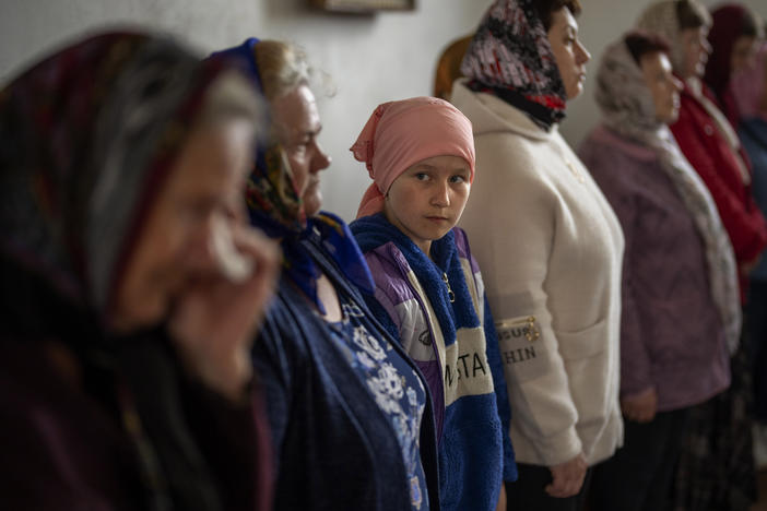 A girl looks as a woman crying during a religious service to commemorate the fallen during the Russian occupation in Zdvyzhivka, on the outskirts of Kyiv, on Saturday.