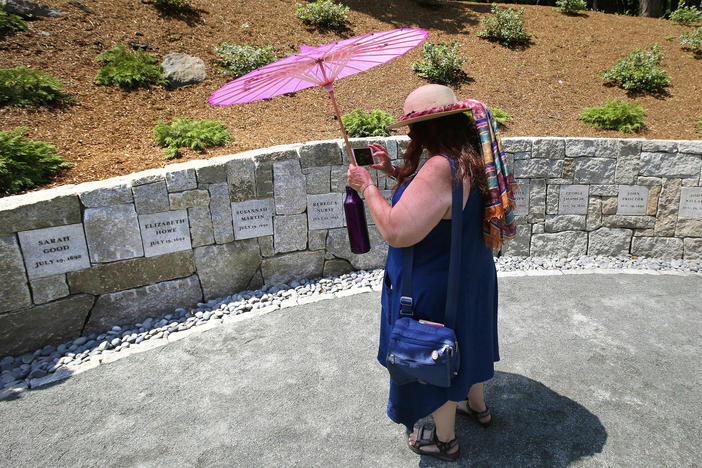 Karla Hailer, a teacher from Scituate, Mass., takes a video on July 19, 2017, where a memorial stands at the site in Salem, Mass., where five women were hanged as witches more than three centuries years earlier. Massachusetts lawmakers on have formally exonerated Elizabeth Johnson Jr., clearing her name 329 years after she was convicted of witchcraft at the height of the Salem Witch Trials.