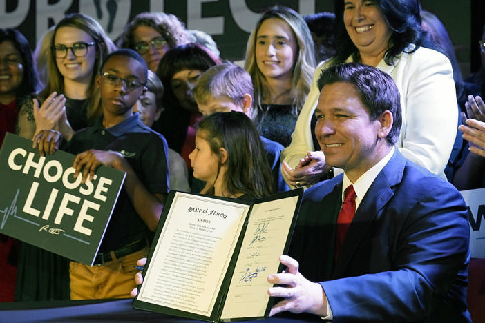 Florida Gov. Ron DeSantis holds up a 15-week abortion ban law after signing it on April 14, in Kissimmee, Fla. A synagogue claims in a lawsuit that the law violates religious freedom rights of Jews in addition to the state constitution's privacy protections.