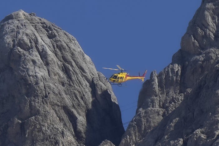 A rescue helicopter hovers over the Punta Rocca glacier near Canazei, in the Italian Alps in northern Italy, Monday, July 4, 2022.