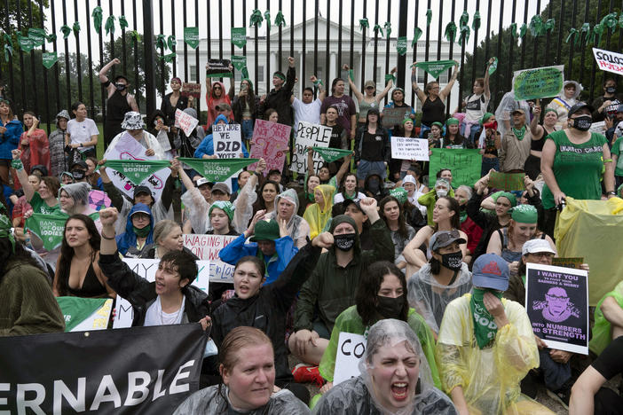 Abortion-rights demonstrators shout slogans after tying green flags to the fence in front of the White House during a protest to pressure the Biden administration to act and protect abortion rights on Saturday.