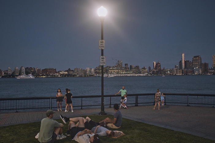People spend time at the park at dusk during a summer heat wave in Hoboken, N.J., on July 21, 2022.