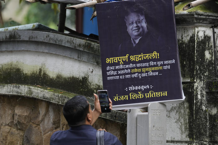 A man takes a picture of a poster paying homage to veteran stock market investor and Indian billionaire Rakesh Jhunjhunwala in Mumbai, India, on Sunday. Jhunjhunwala, died at the age of 62.