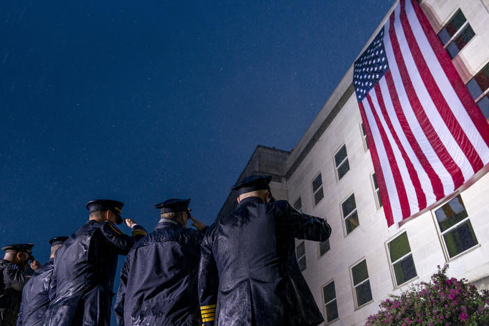 First responders salute in a driving rain as a U.S. flag is unfurled at the Pentagon on Sunday, the 21st anniversary of the 9/11 attacks.