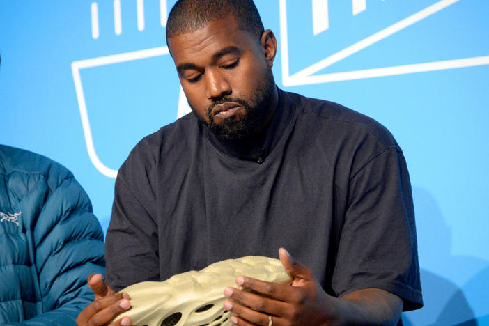 Kanye West holds a Yeezy shoe as he speaks on stage at the "Kanye West and Steven Smith in Conversation with Mark Wilson" at the on Nov. 7, 2019 in New York City.