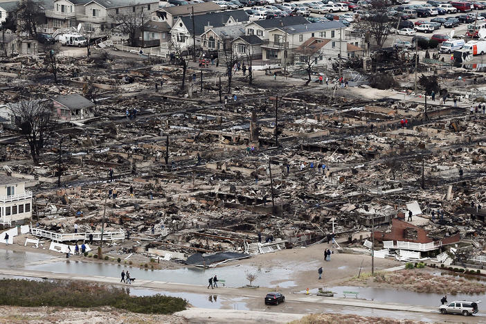 People walk near the remains of burned homes after Hurricane Sandy in the Breezy Point neighborhood of the Queens borough of New York City on Oct. 31, 2012. Over 50 homes were reportedly destroyed in a fire during the storm.