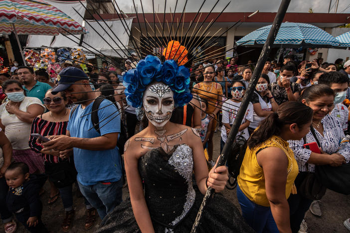 A young woman dressed in Santa Muerte makeup waits outside the pantheon with other participants.