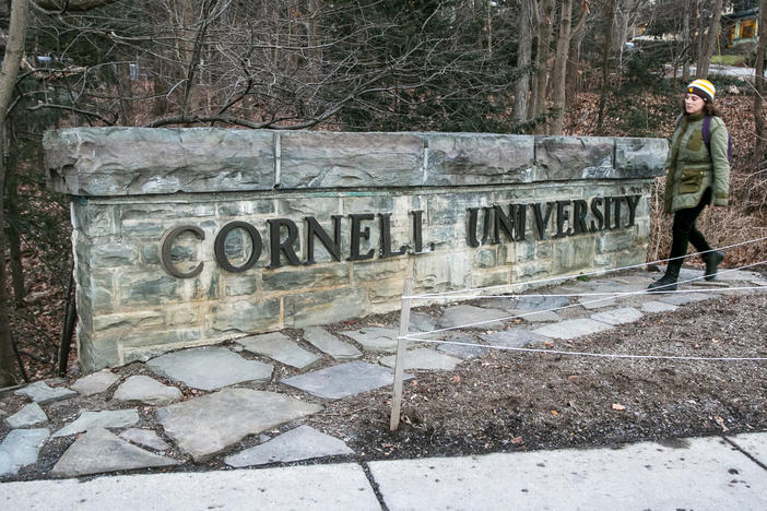 A woman walks by a Cornell University sign on the Ivy League school's campus in Ithaca, N.Y.