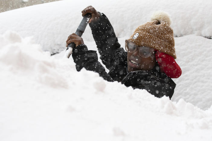 Zaria Black, 24, from Buffalo, clears off her car as snow falls Friday, Nov. 18, 2022, in Buffalo, N.Y.