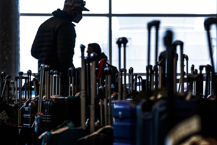 Travelers search for their suitcases in a baggage holding area for Southwest Airlines at Denver International Airport on Dec. 28 in Denver, Colo.