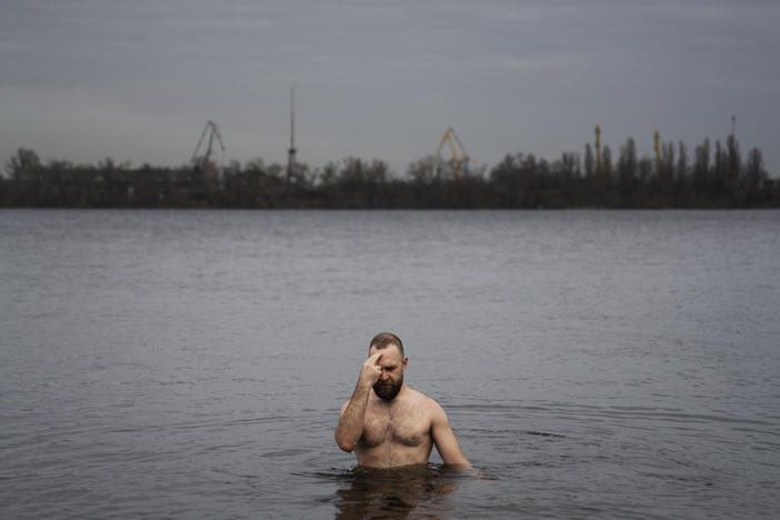 Nikolai Pastuchenko crosses himself as he takes a dip into the Dnipro River in Dnipro, Ukraine, on Thursday.