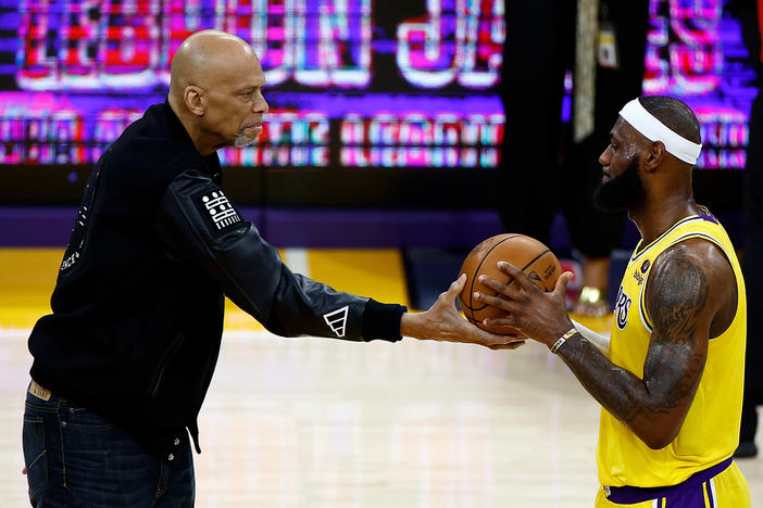 Kareem Abdul-Jabbar (left) hands LeBron James a basketball celebrating James' all-time NBA scoring record Tuesday night in Los Angeles.
