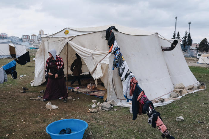 A 26-year-old pregnant woman named Talibe Gezginci cleans her tent in a makeshift camp for displaced people in Gaziantep.