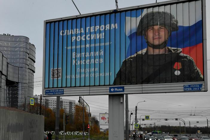 A poster displays a Russian soldier with a slogan reading "Glory to the Heroes of Russia."