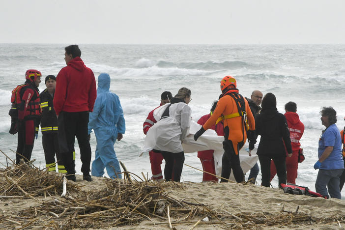 Rescuers recover a body at a beach near Cutro, southern Italy, after a migrant boat broke apart in rough seas, Sunday, Feb. 26, 2023. Rescue officials say dozens of migrants have died after their boat broke apart off southern Italy.
